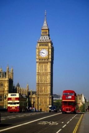Big Ben, London, with two red double-decker buses driving by.
