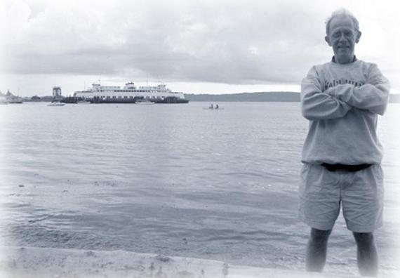 A blue-tinted picture of John Webster, posing in front of a ferry.