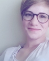 A headshot of a woman with short hair and glasses.