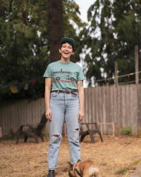 White person smiling in a backyard by a dog