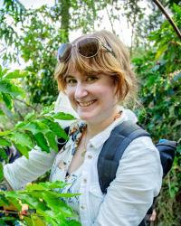 A picture of a woman standing next to plants