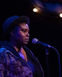 Photo of Rasheena Fountain standing at a microphone 