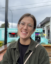 woman sitting outside on patio with food truck behind her