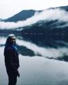 Woman with blue hair in a red leather jacket standing in front of Lake Crescent
