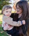 Kait is a white woman with long brown hair, hazel eyes, and round brown glasses. In this image, she's holding her two-year-old nephew, Carter.