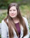 Portrait photo of Anna Preus, a white woman wearing a grey blazer and maroon shirt