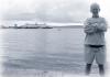 A blue-tinted picture of John Webster, posing in front of a ferry.