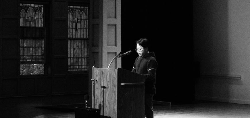 MFA student reader at a podium in black and white